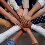 Diverse people putting hands in to signify teamwork