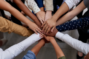 Diverse people putting hands in to signify teamwork